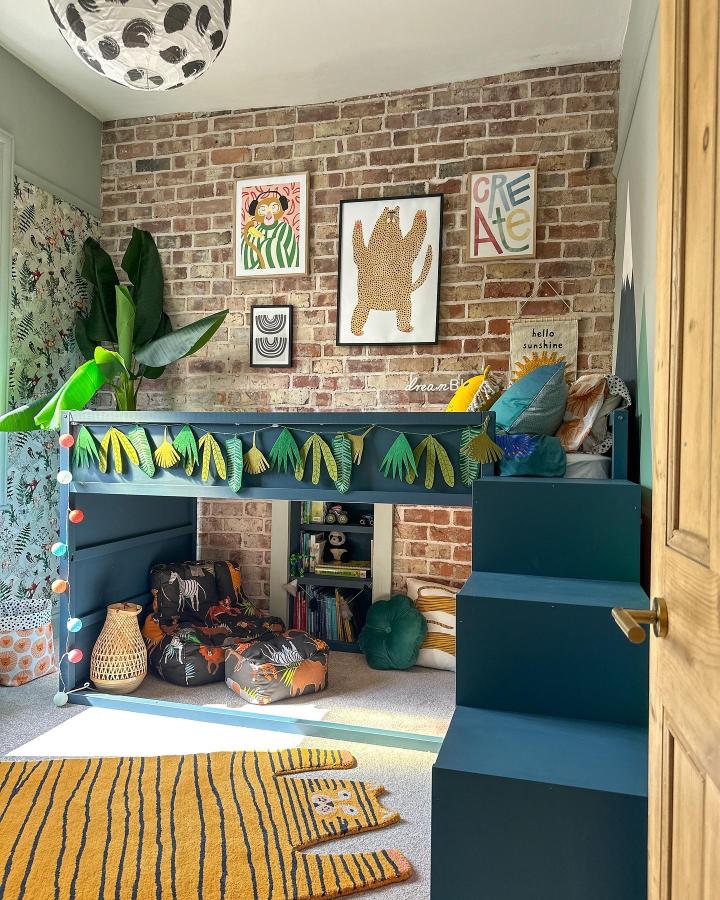 Dark teal jungle-themed boysโ bedroom KURA bed from @little_edwardian_semi. Raised nook with leafy bunting and seating.