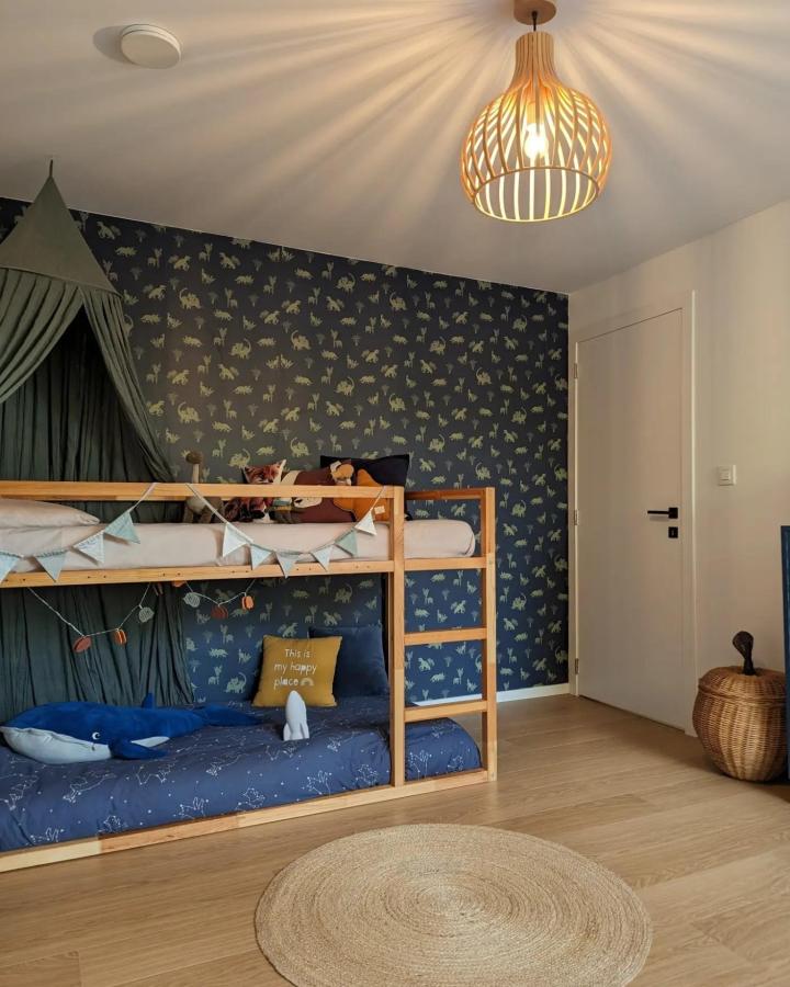 Navy dinosaur Kura bunk bed from @a.house.to.go.home.to. Natural pine frame, bunting, and cozy blue bedding.