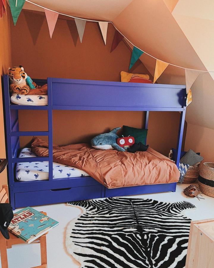 Blue-painted bunk bed from @debbiehendriks_styling. Playful boysโ bedroom with bunting, storage drawers, animal cushions, and zebra rug.