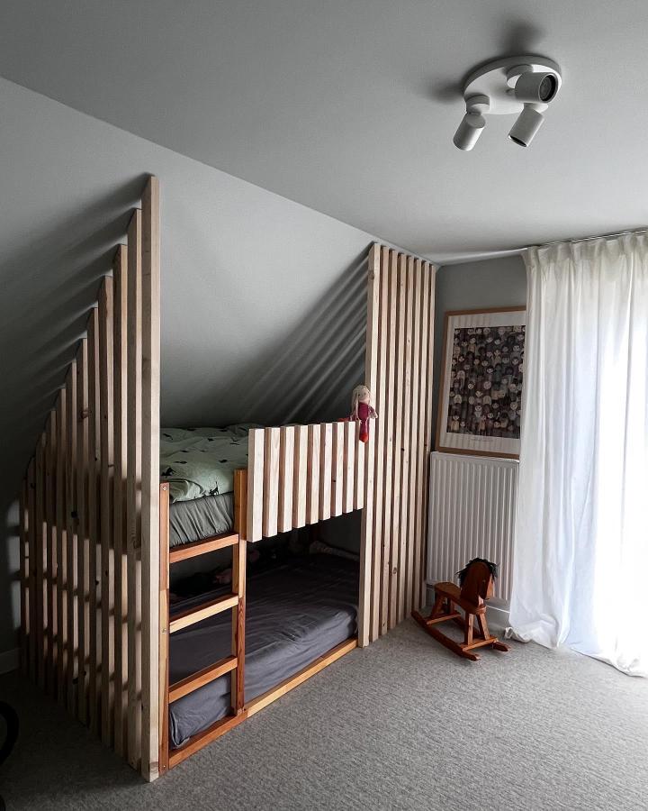Natural wood slat bunk bed from @das_spechthaus. Cozy enclosed KURA design with sage bedding and gray walls.
