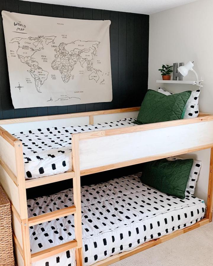 Black-paneled shared room from @hivelane. This image suits ikea kura bed ideas for shared rooms with green pillows.