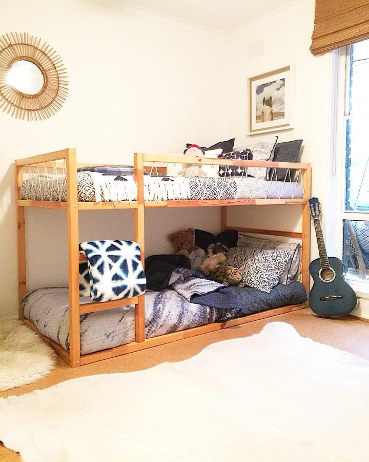 Warm natural-wood bunk bed from @mrs.schmick. Cozy shared bedroom with patterned bedding, rope rails, and layered pillows.