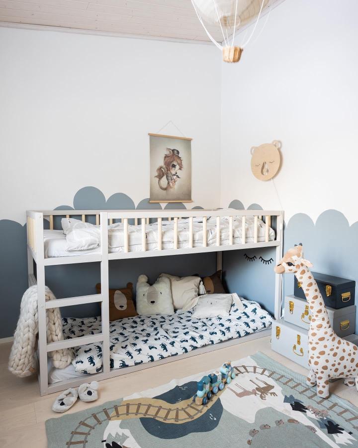 Soft blue shared-room bunk from @tuoksuajatunnelmaa. White KURA bed, scalloped wall, plush toys, and woodland bedding.