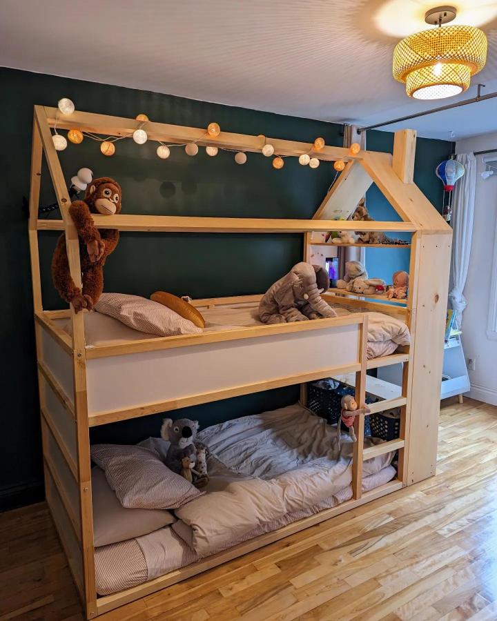 Natural wood house-frame bunk from @sebastiendalgo. Cream-panel ikea kura bed ideas for shared rooms with string lights.