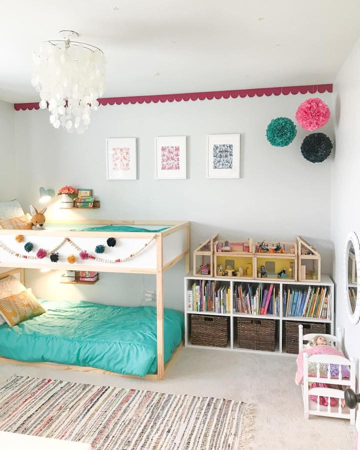 Turquoise shared-room Kura bunk from @oakstorydesign. Light wood frame, colorful garlands, and cozy bedding.