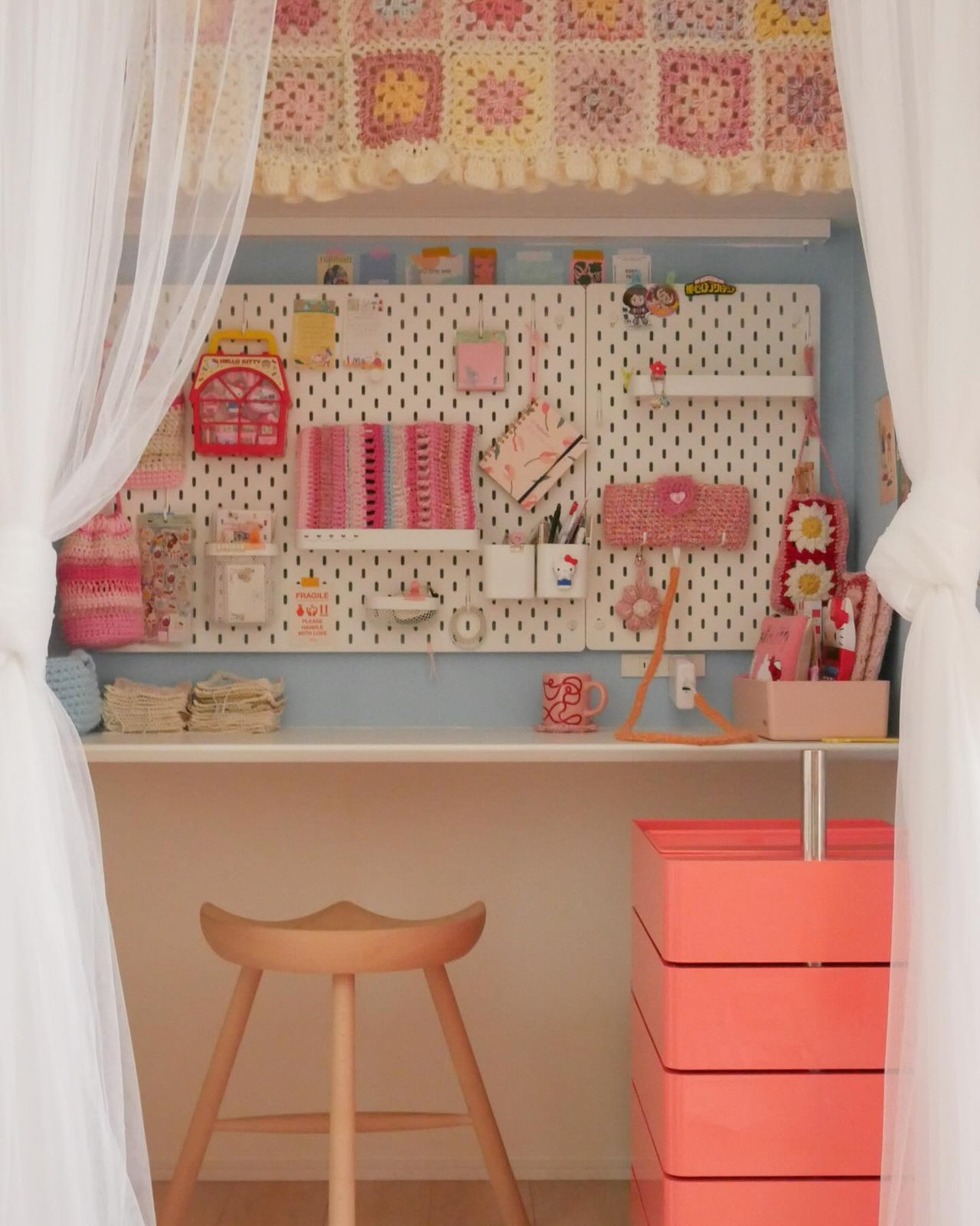 Colorful pegboard craft nook with crochet storage, shelves, and handmade supplies