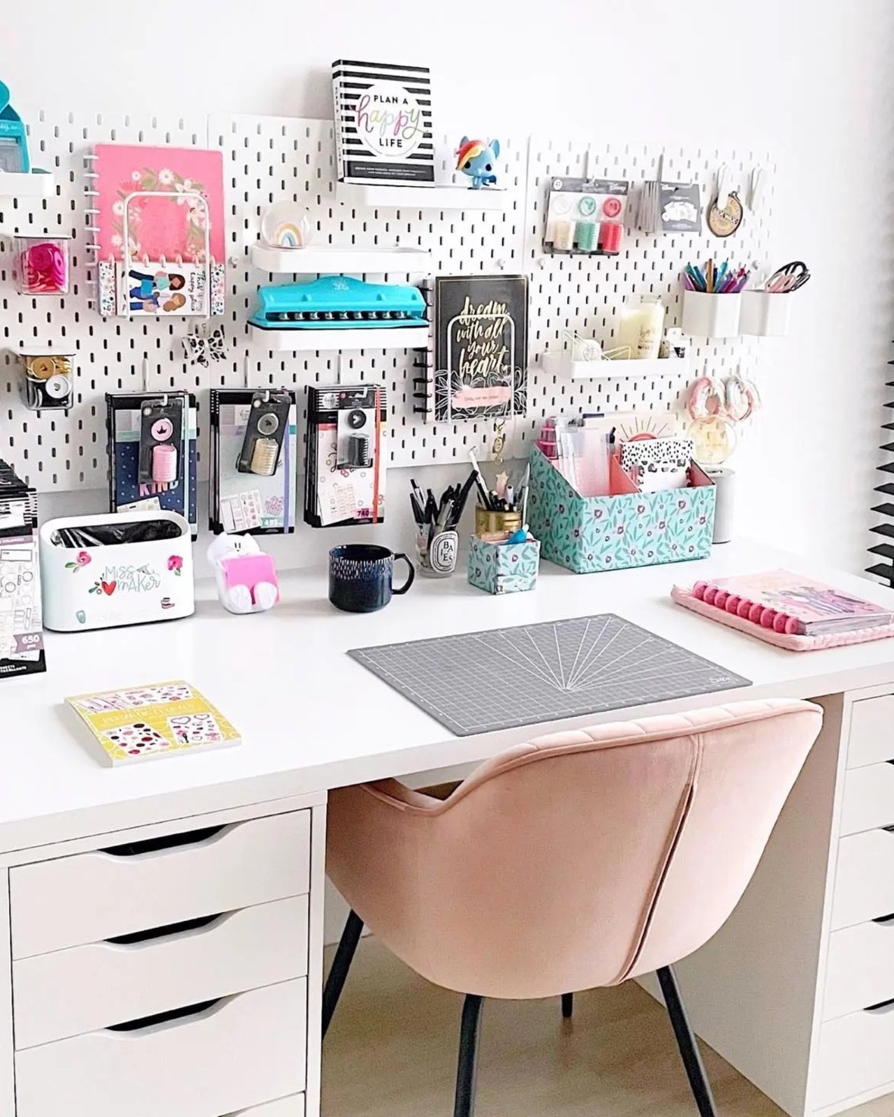 White pegboard craft station with colorful supplies, shelves, baskets, and organized Skadis storage