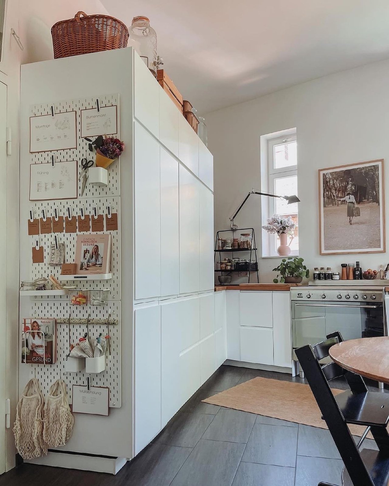 White pegboard craft storage beside cabinetry with labeled cards, shelves, baskets, scissors, books, and handmade bags
