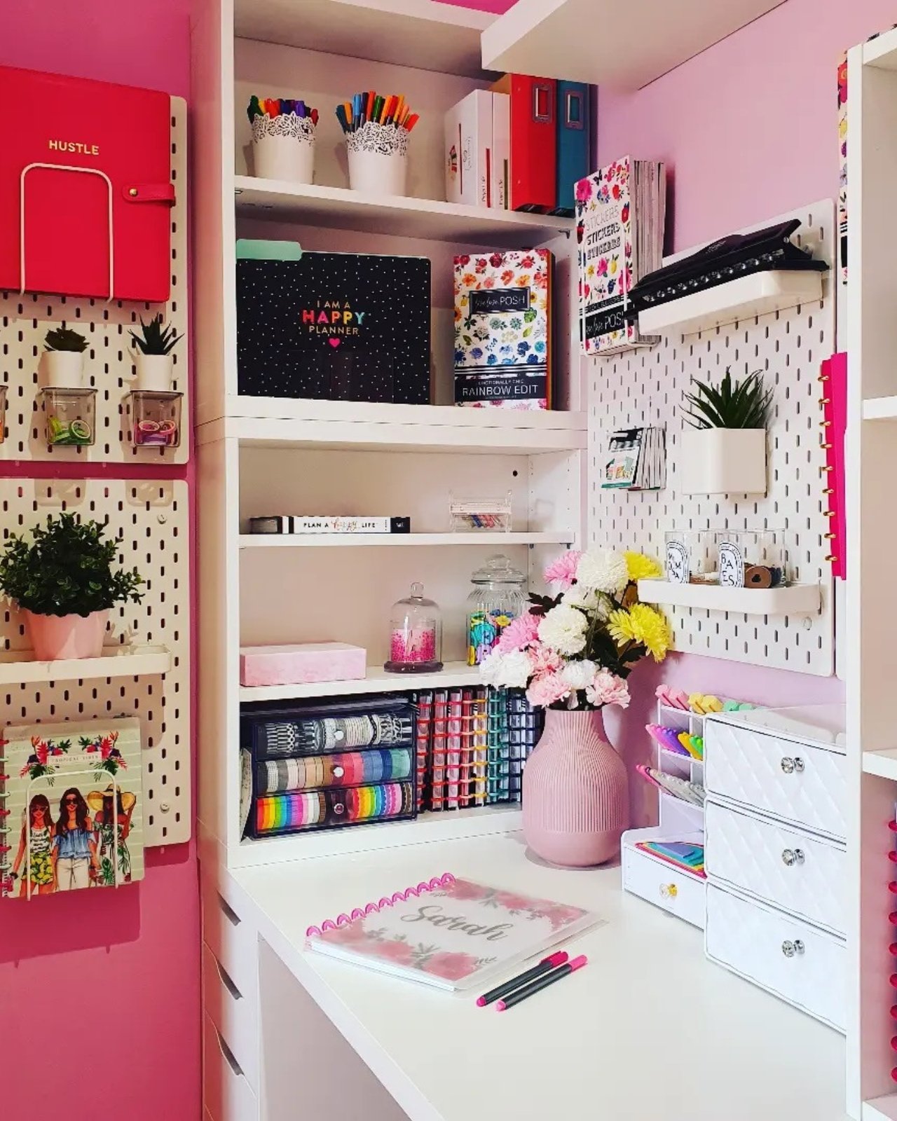 Colorful pegboard craft room with shelves, planners, pens, ribbons, plants, and organized creative supplies